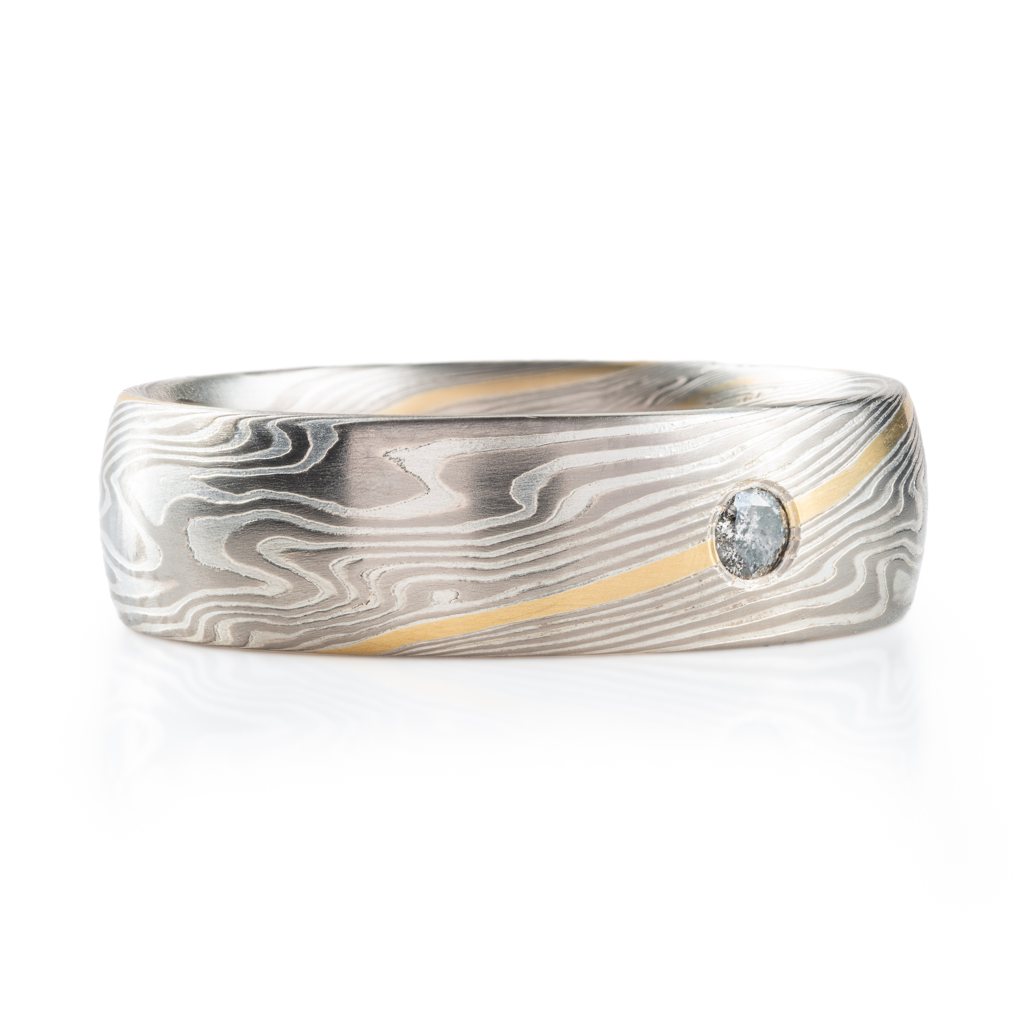 mokume gane ring made of light and dark silver layers with one layer of yellow gold, with a single round flush set salt and pepper diamond.