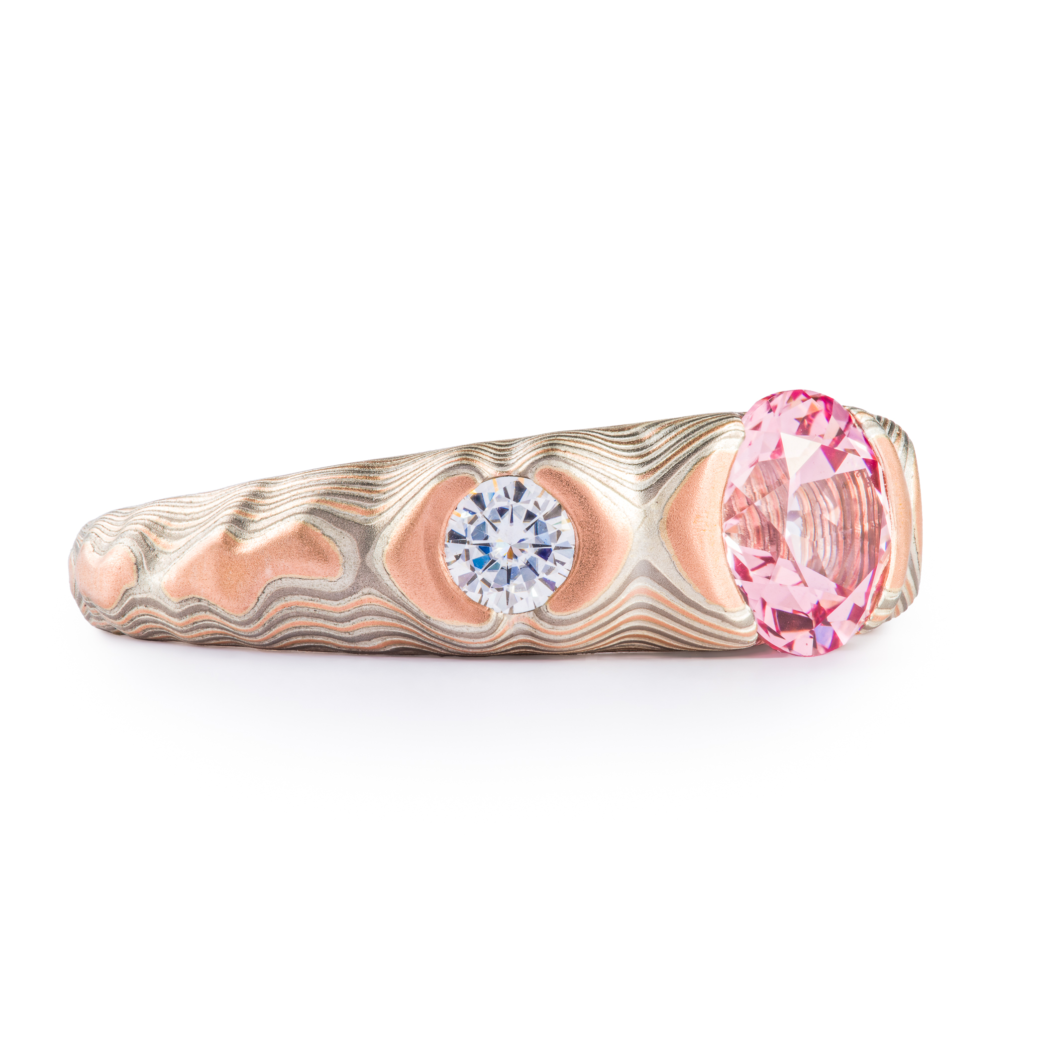Tapered red gold, palladium and silver mokume gane patterned ring, cathedral style setting with a large pink stone, flanked on each side by a smaller white stone.