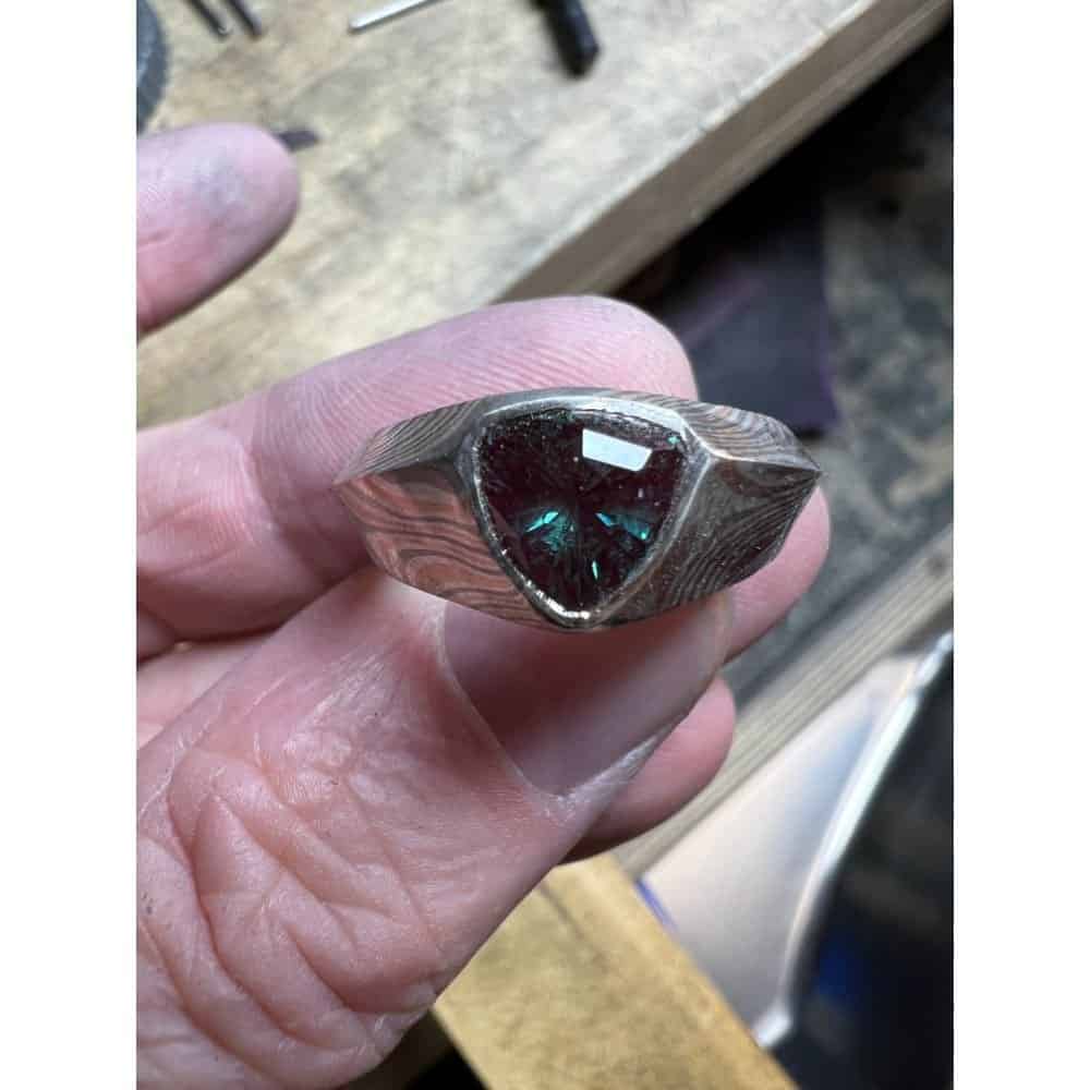 mokume gane cathedral style ring holding a large trillion shaped sapphire, before finishing