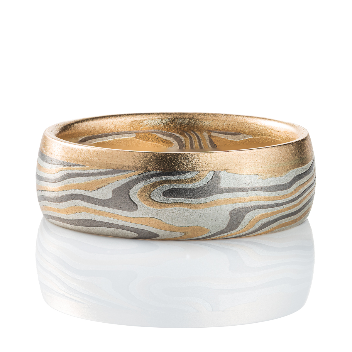 Mokume gane ring made of twisting layers of oxidized silver, palladium and yellow gold, with a solid strip of yellow gold running around one edge.