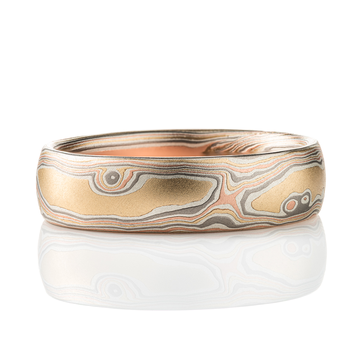 warm yellow gold mokume gane patterned band, twisting and organic flowing pattern, made with layers of red gold, yellow gold, palladium, and oxidized silver.