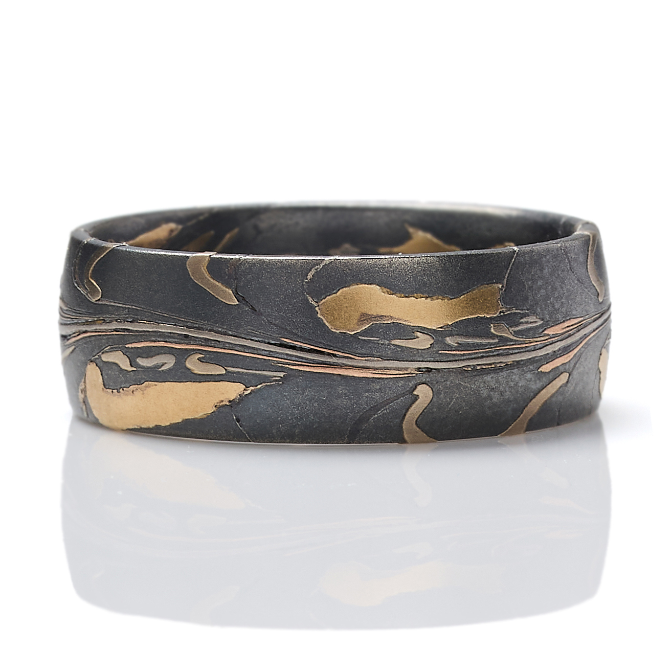 Arn Krebs mokume gane mens ring made in an organic unique pattern, with layers of yellow gold, red gold, palladium, and silver that's been oxidized. The pattern resembles pressed flower petals on a dark backdrop.